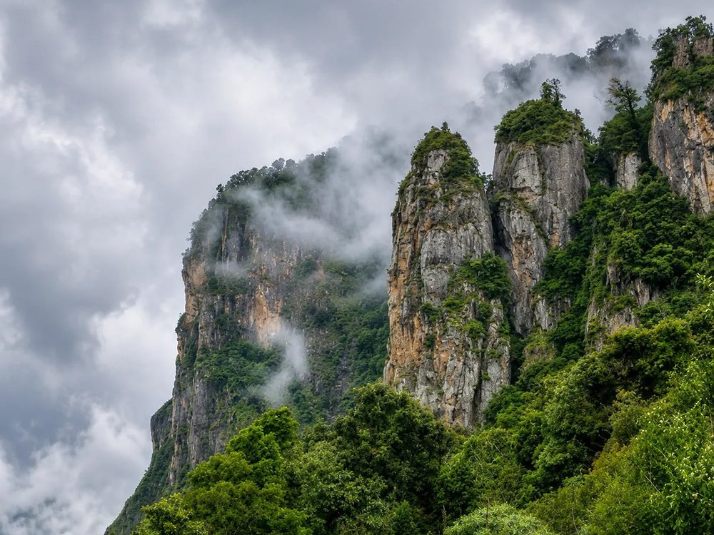 Misty rock cliffs and green forest at Kodaikanal